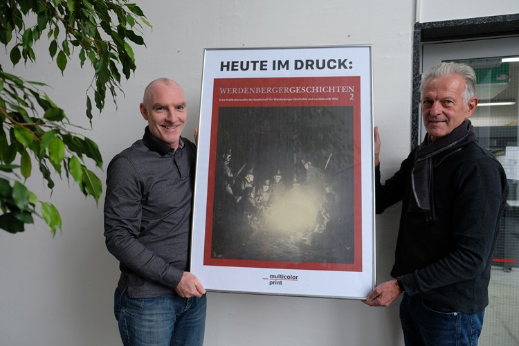Der Stv. Leiter von bmedien Werner Sivec und der Buchlayouter Peter Freudemann mit dem Plakat zum freudigen Tag.