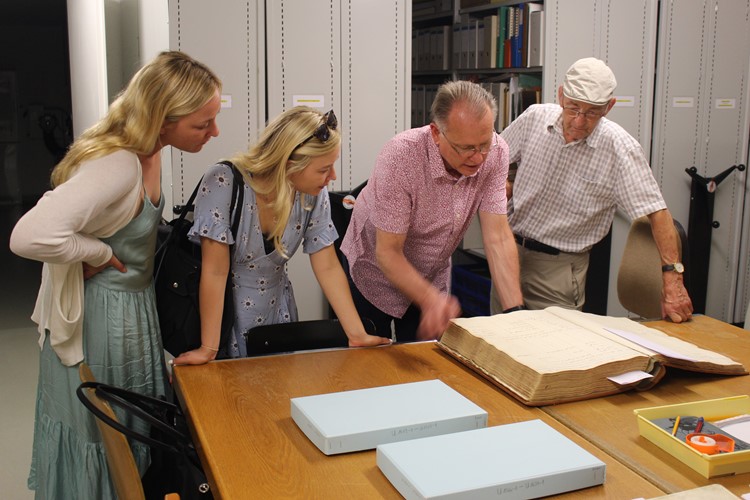 Mathäus (Debis) Lippuner (rechts) zeigt der Familie Robinson im Grabser Ortsarchiv die alten Familienbücher und Taufregister, worin sie die Namen ihrer Vorfahren entdecken.